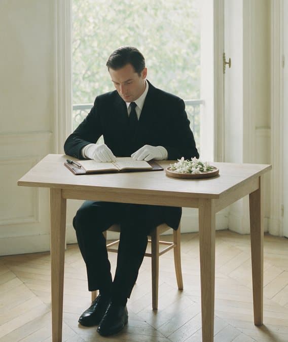 Un compositeur note la direction olfactive d'une marque, un plateau de jasmin posé sur la table.